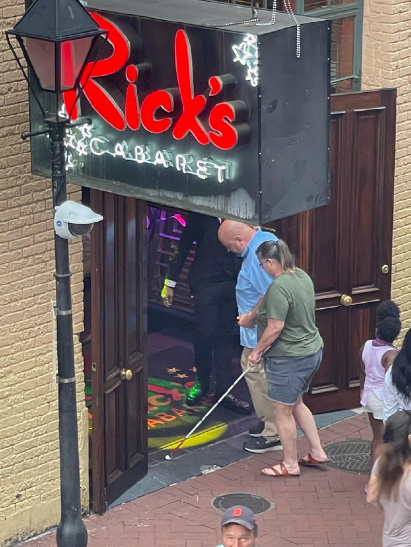 Husband leading blind wife into strip club